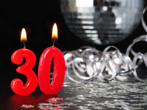red 30th birthday candles with silver decorations in background