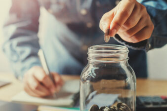 man putting a coin into a glass jar