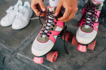 girl lacing up pink roller stakes