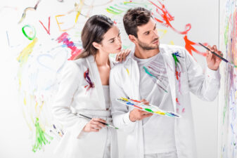 couple wearing all white and painting together in different colors