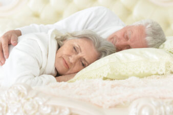 happy senior couple sleeping in bed