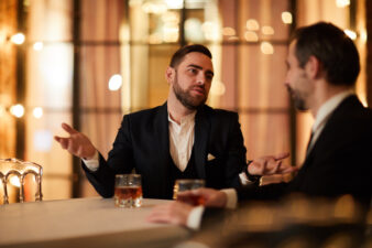 business man speaking with another man while drinking scotch