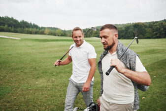 two men carrying golf clubs