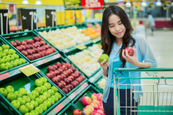 woman deciding between two apples at the grocery store