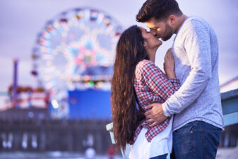 couple kissing with a Ferris Wheel in the background