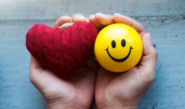 hands holding a heart and a smiley face ball