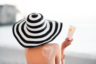 woman putting on heart in sunscreen on back