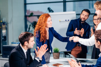 redheaded woman shaking hands at a business meeting