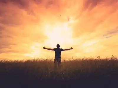 silhouette of man with arms spread to the sunrise