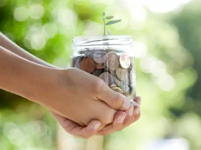hand holding a jar full of growing coins