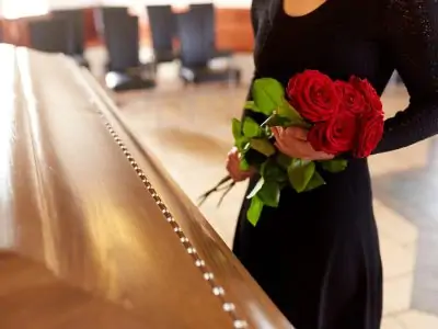 woman with red roses and coffin at funeral